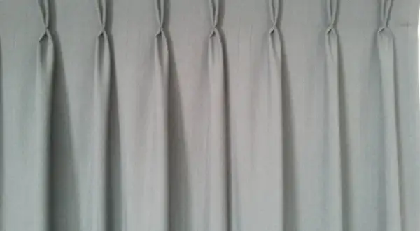 Cortina gris con pliegues de pinza, un ejemplo de los tipos de confección de cortinas que aportan elegancia y estructura.