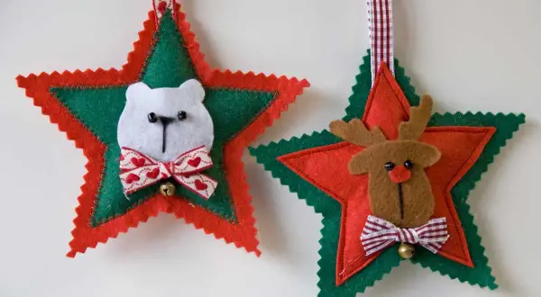 Adornos navideños de fieltro: un oso polar y un reno adornan estrellas rojas y verdes, listos para colgar.