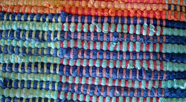 Textura de alfombra tejida a mano con hilos de colores: naranja, azul y verde. Ideal para aprender como hacer una alfombra.