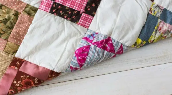 Colchas patchwork fáciles de hacer, con retazos de tela de flores, cuadros y rayas, sobre una mesa de madera.