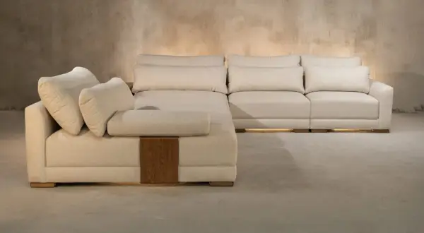 Sofá modular beige con cojines mullidos, detalles de madera y una textura que evoca nombres de telas como lino o algodón.