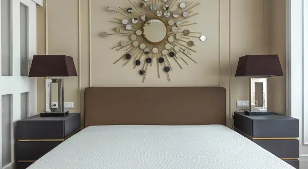 Un espejo sol y lámparas oscuras iluminan la habitación, demostrando como alegrar una habitación con muebles oscuros.