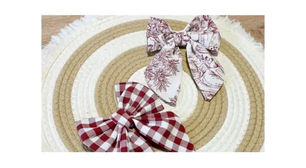Dos lazos de tela, uno a cuadros rojos y blancos, otro con estampado floral en tonos burdeos, descansan sobre un tapete circular de cuerda.
