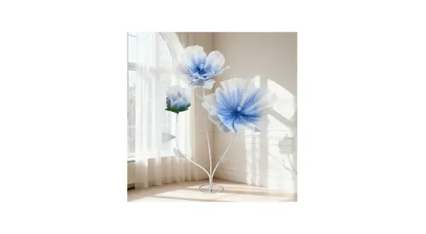 Tres flores de tela grandes, azules y blancas, con tallos blancos, junto a una ventana con cortinas.