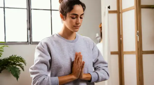 Mujer practicando mindfulness para combatir el insomnio, con las manos juntas en posición de rezo.
