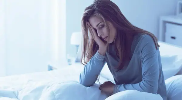 Mujer en la cama, con la mano en la frente, parece que me duermo y me despierto a cada rato.