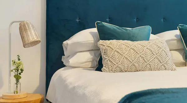 Cabecero de tela azul, almohadas y cama lista. Aprende como limpiar cabecero de tela para mantenerlo impecable.