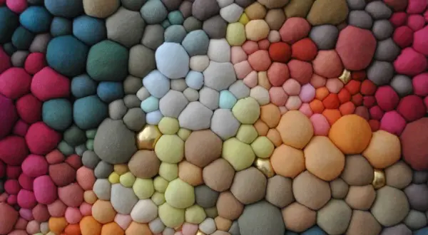 Textura orgánica de burbujas de **fibras sintéticas** en degradado de colores, con toques dorados.
