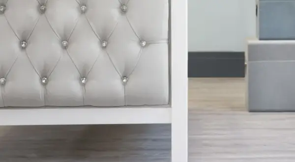 Detalle de un cabecero capitoné gris con botones de cristal. El capitoné es una técnica de tapicería que crea un efecto acolchado y lujoso.