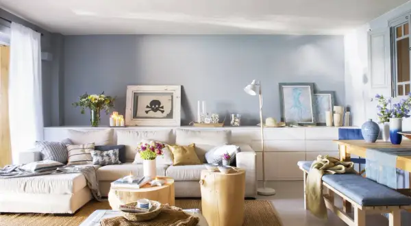 Sofá beige y cojines azules crean un ambiente acogedor. Tonos tierra y marinos se combinan en esta sala.
