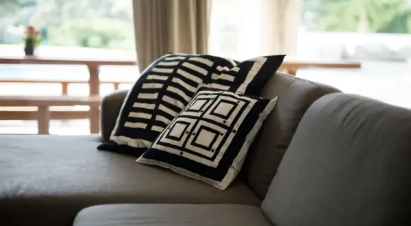 Sofá gris con cojines de diseño geométrico blanco y negro. Un detalle perfecto para combinar sofá negro y crear un ambiente moderno.
