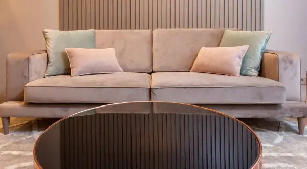 Sofá beige con cojines pastel. Aprende como limpiar un sofa antimanchas para mantenerlo impecable.