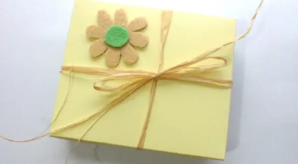 Caja amarilla decorada con flor de fieltro y lazo de rafia. Ideas de manualidades con fieltro para el hogar.