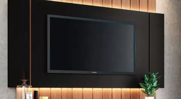 Elegante decoración pared TV salón con panel negro, listones de madera y luz cálida. Un toque moderno y acogedor.