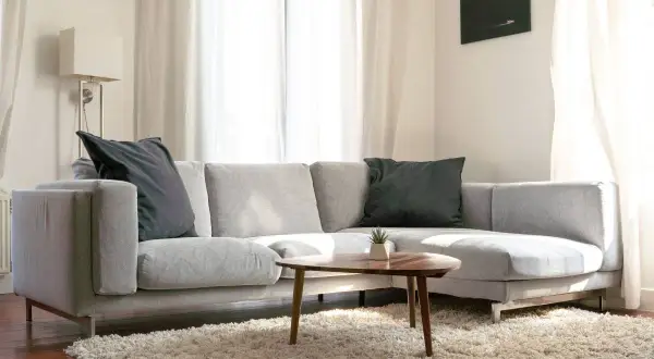 Sofá chaise longue gris con cojines oscuros, ideal para aprender como colocar cojines en chaise longue y crear un rincón acogedor.