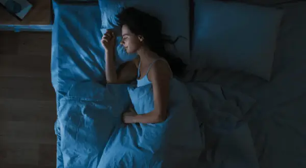 Mujer durmiendo plácidamente, buscando cómo dormir con calor y sin aire acondicionado.