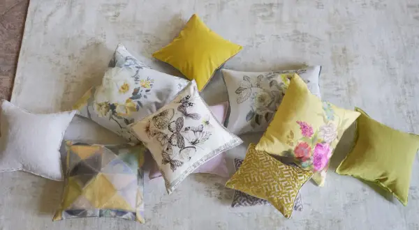 Varios cojines decorativos, algunos con estampados florales y mariposas, otros con diseños geométricos, todos son cuadros hechos con retazos de tela.