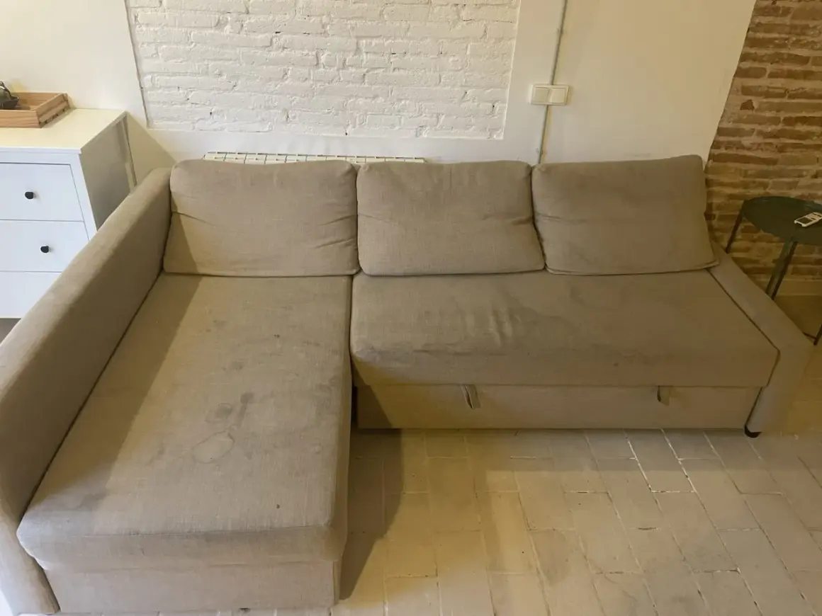 Sofá seccional beige con manchas, ideal para aprender como quitar manchas de chocolate del sofá.