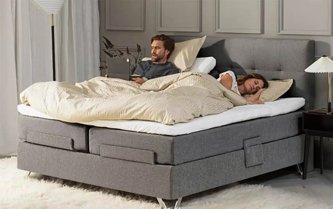 Hombre despierto en cama con portátil, mujer durmiendo a su lado. Un momento de paz para dormir juntos.