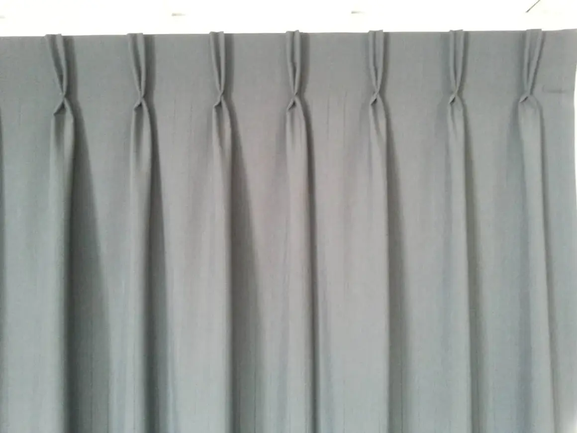 Cortina gris con pliegues de pinza, un ejemplo de los tipos de confección de cortinas que aportan elegancia y estructura.