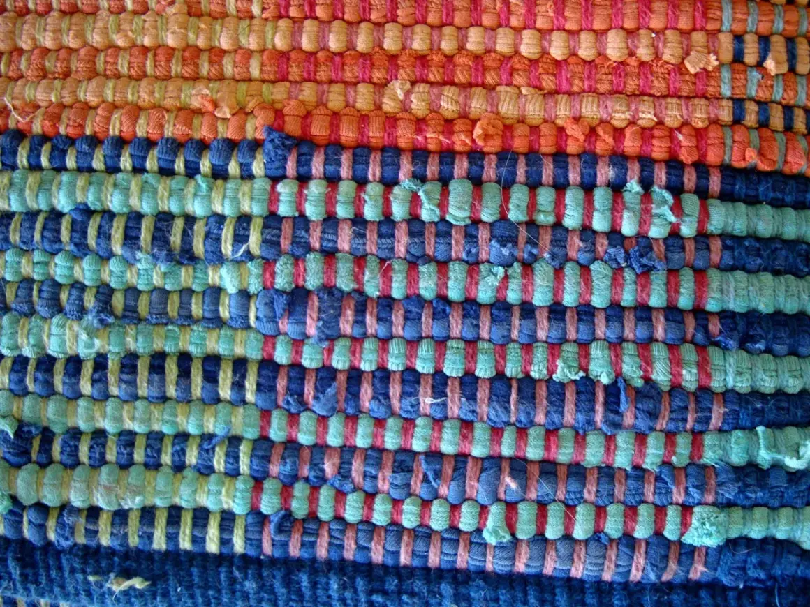Textura de alfombra tejida a mano con hilos de colores: naranja, azul y verde. Ideal para aprender como hacer una alfombra.