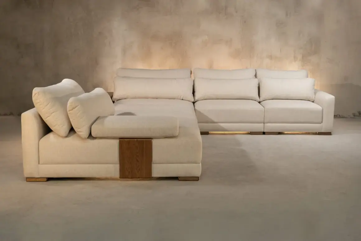 Sofá modular beige con cojines mullidos, detalles de madera y una textura que evoca nombres de telas como lino o algodón.