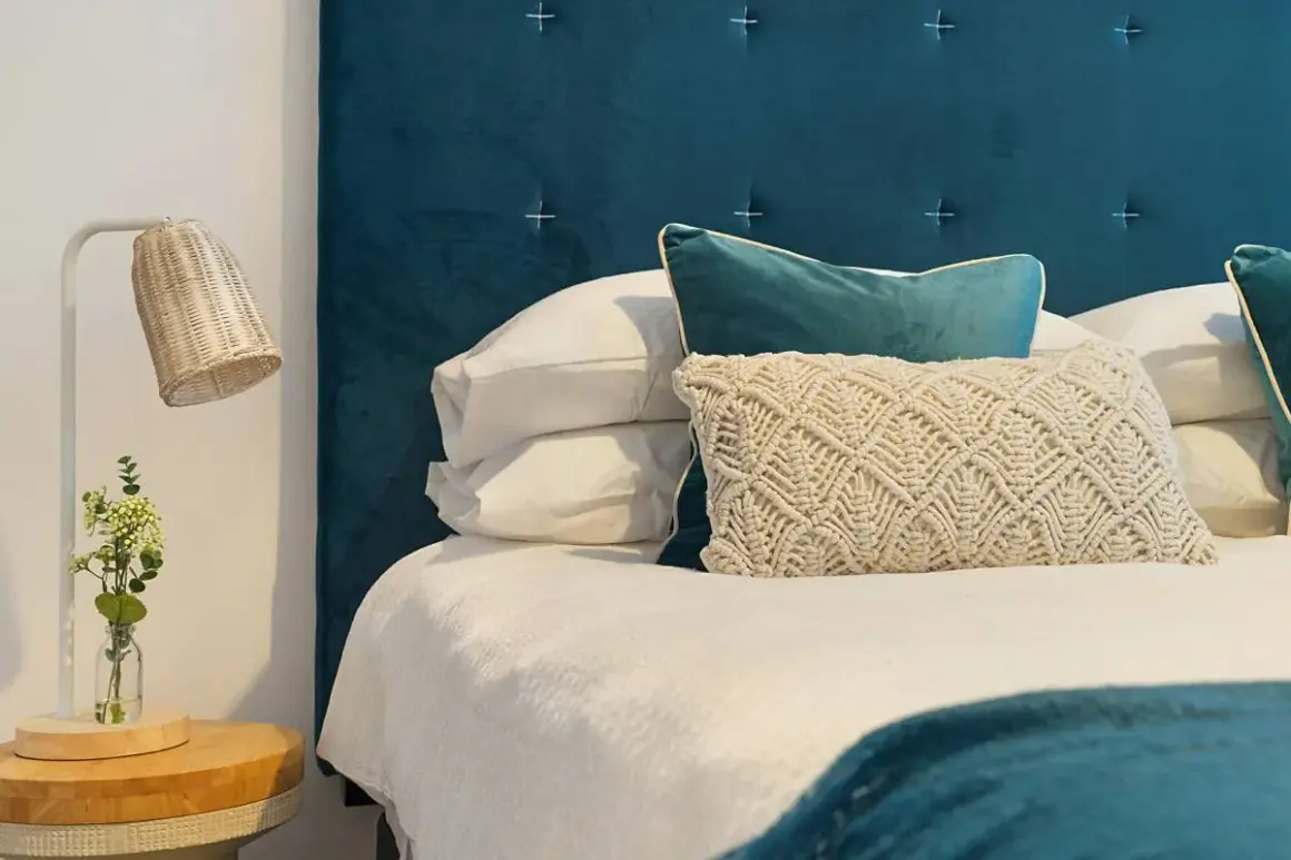 Cabecero de tela azul, almohadas y cama lista. Aprende como limpiar cabecero de tela para mantenerlo impecable.