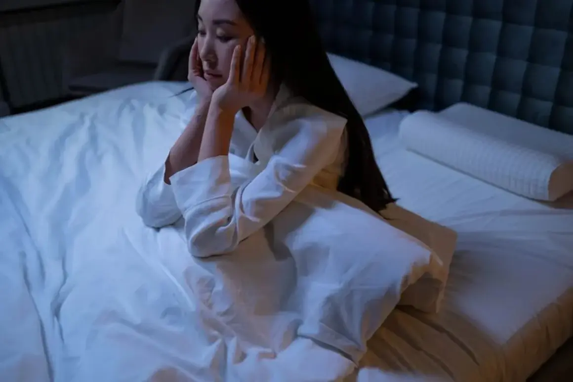 Me despierto de madrugada y no puedo volver a dormir. Una mujer sentada en la cama, con las manos en la cara, mirando al vacío.