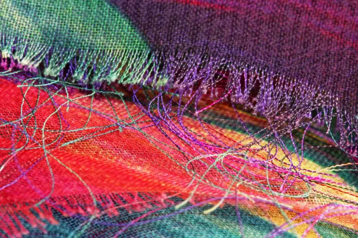 Detalle de tela con hilos sueltos de colores vibrantes. Se aprecia el tejido y cómo se puede coser a mano para que no se deshilache.