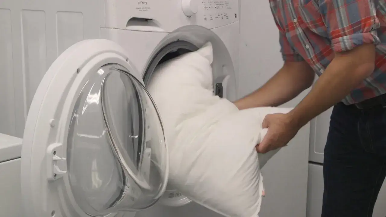 Hombre mete coj&iacute;n de espuma en lavadora. Aprende c&oacute;mo lavar cojines de espuma en lavadora para mantenerlos frescos.