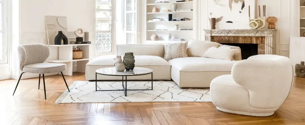 Un cómodo sofá en medio del salón, rodeado de decoración moderna y una chimenea clásica.
