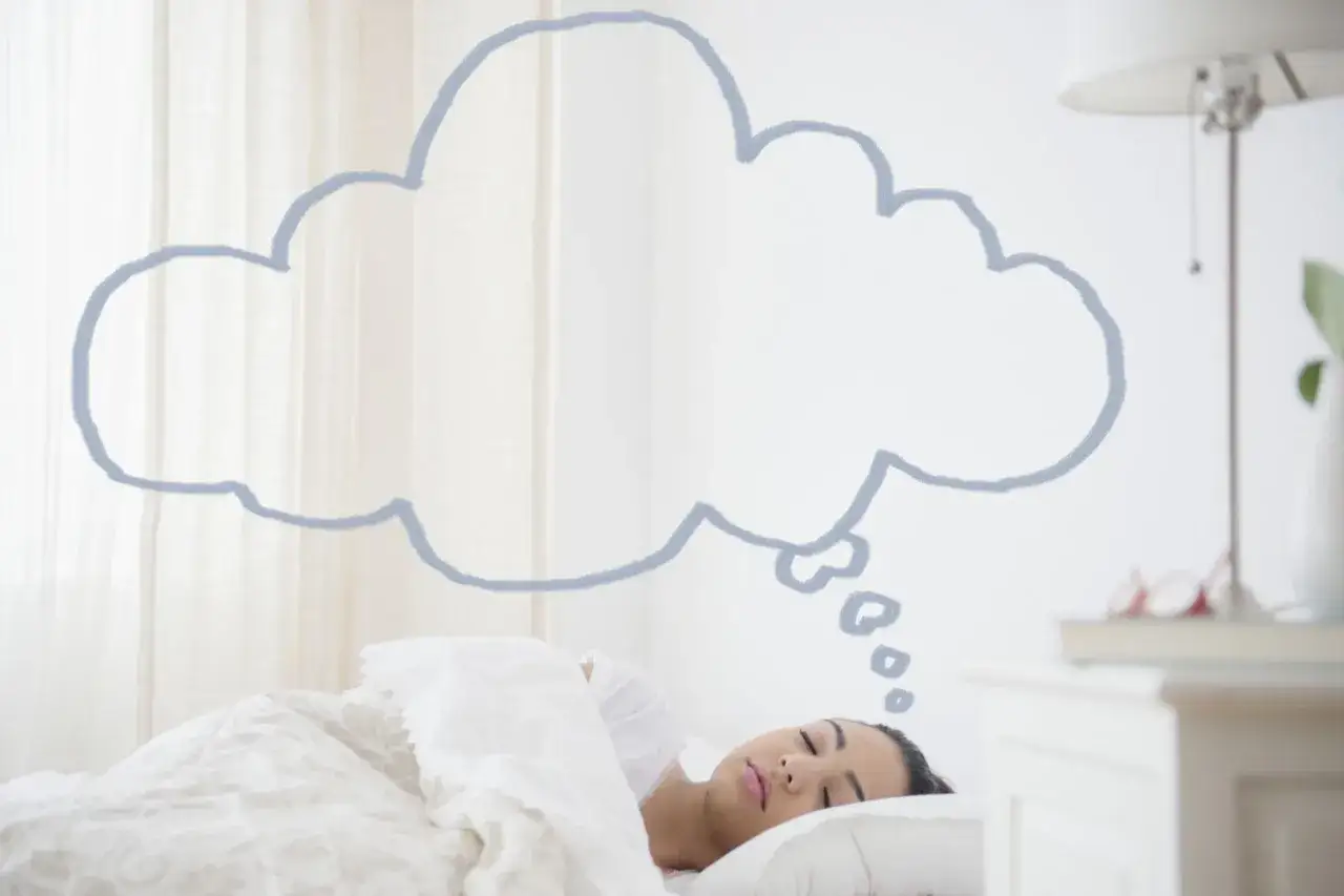 Una mujer duerme plácidamente mientras una nube de pensamiento dibuja curiosidades de los sueños sobre su cabeza.