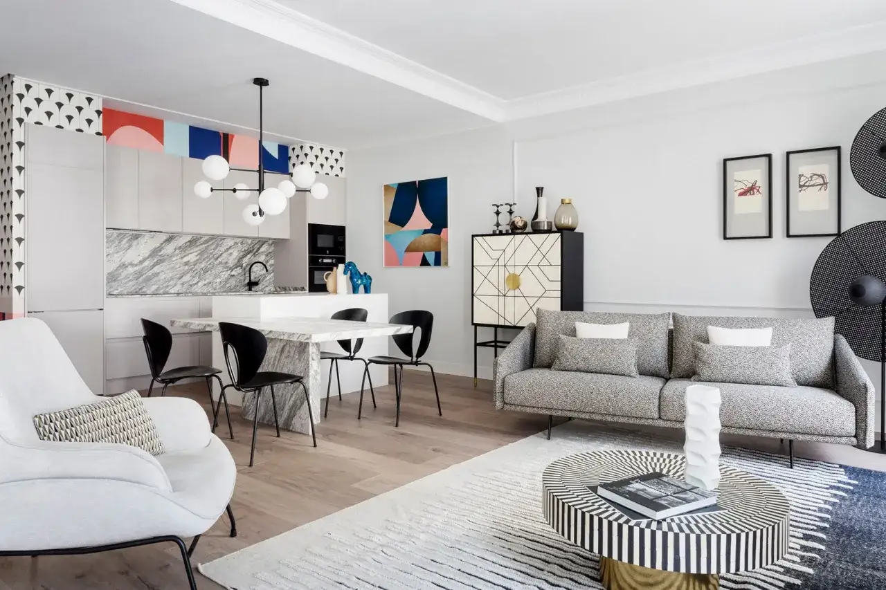 Un sal&oacute;n moderno con detalles de patchwork f&aacute;ciles de recrear. Sof&aacute; gris, mesa de centro geom&eacute;trica y cocina integrada.