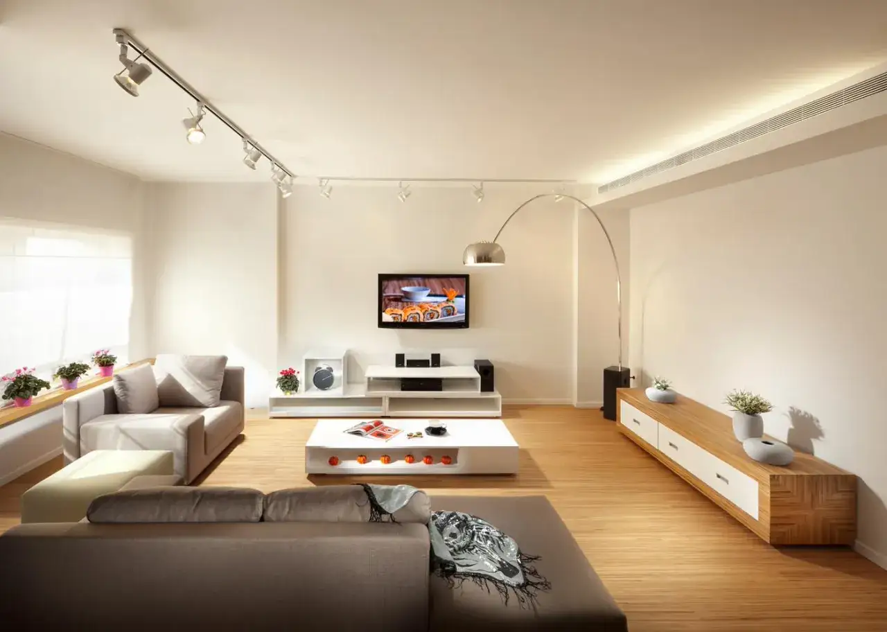 Iluminaci&oacute;n moderna: c&oacute;mo distribuir focos en el techo para crear ambiente en un sal&oacute;n con sof&aacute;s, TV y mesa de centro.