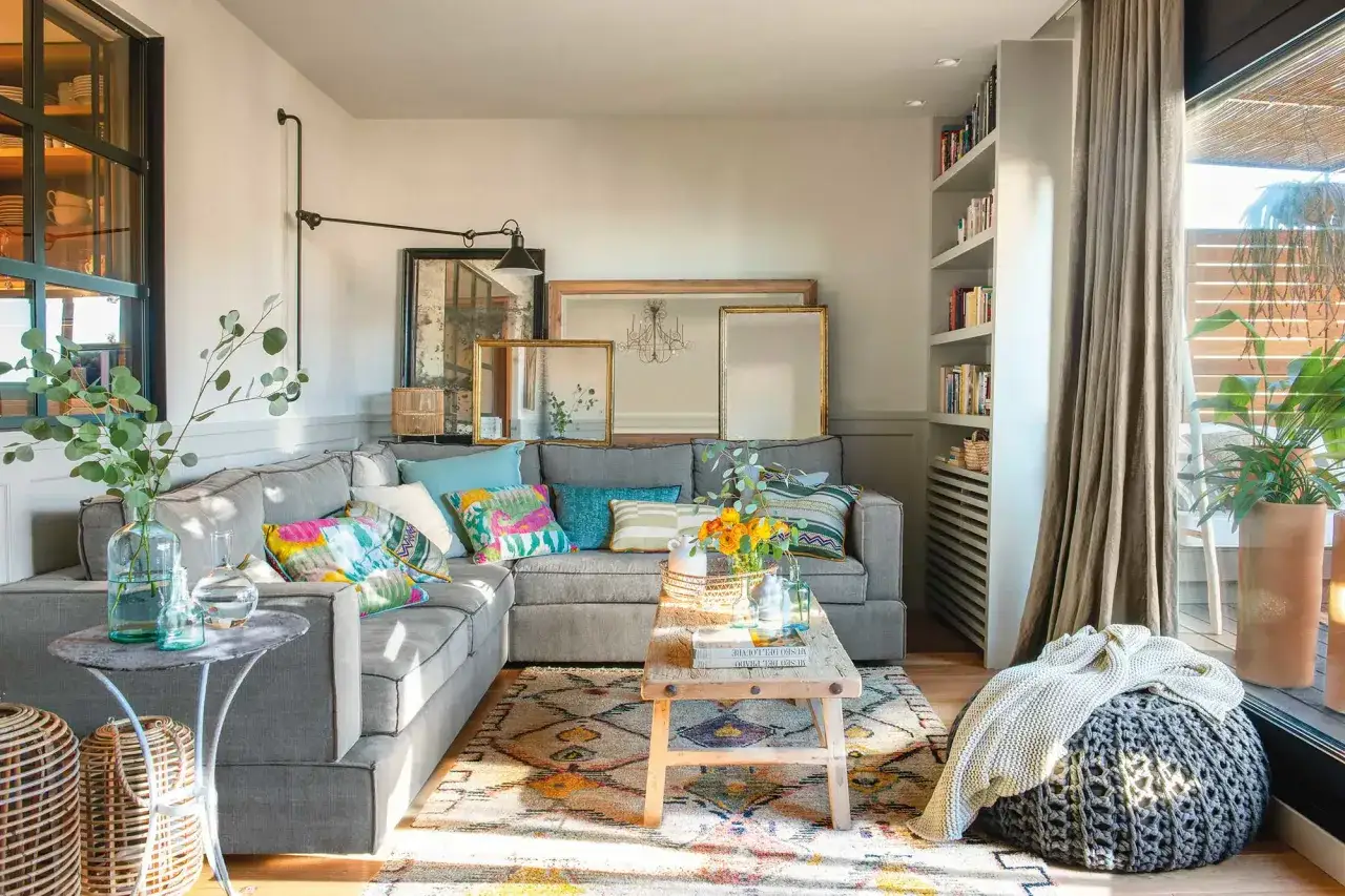 Sof&aacute; gris con cojines coloridos, alfombra &eacute;tnica y plantas. Ideas para decorar rincones peque&ntilde;os con estilo y calidez.
