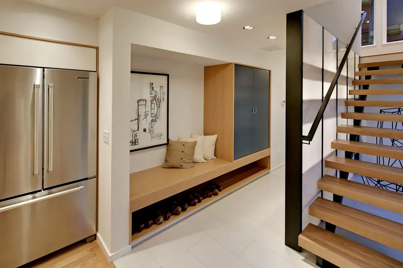 Ideas para decorar un pasillo: refrigerador, banco de madera con cojines, armario azul, estante para zapatos y escaleras flotantes.