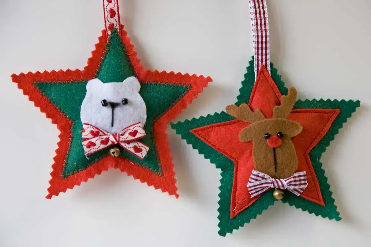 Adornos navideños de fieltro: un oso polar y un reno adornan estrellas rojas y verdes, listos para colgar.