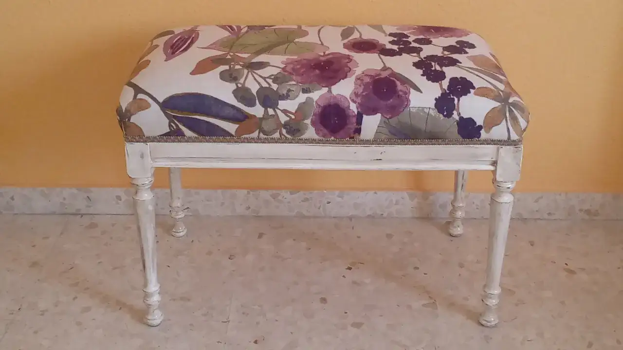 Descalzadora con tapizado floral en tonos morados y verdes, patas blancas desgastadas.