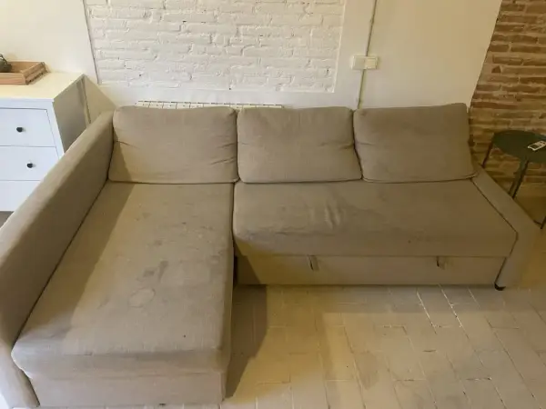 Sofá seccional beige con manchas, ideal para aprender como quitar manchas de chocolate del sofá.