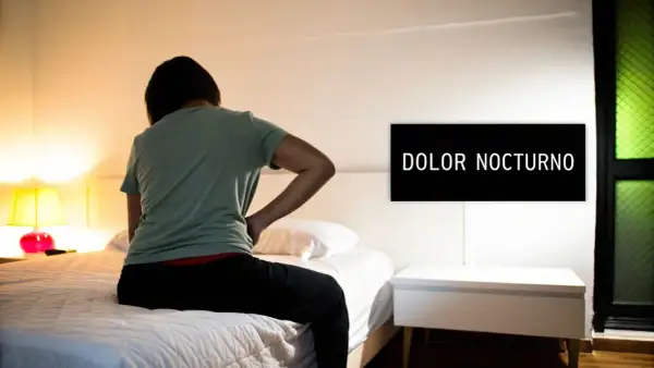 Persona con dolor de espalda sentada en la cama, buscando cómo dormir con hernia discal. El letrero dice "DOLOR NOCTURNO".