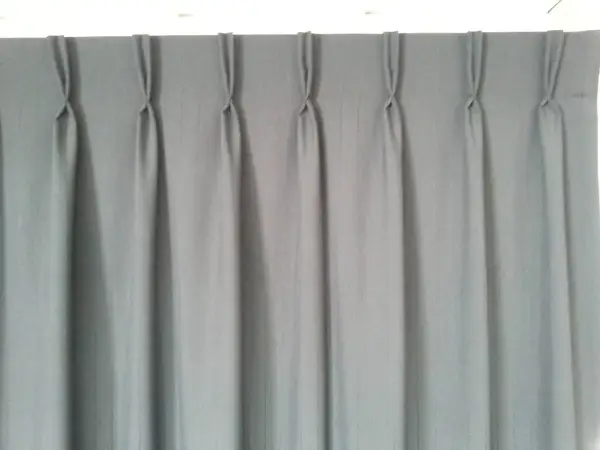 Cortina gris con pliegues de pinza, un ejemplo de los tipos de confección de cortinas que aportan elegancia y estructura.