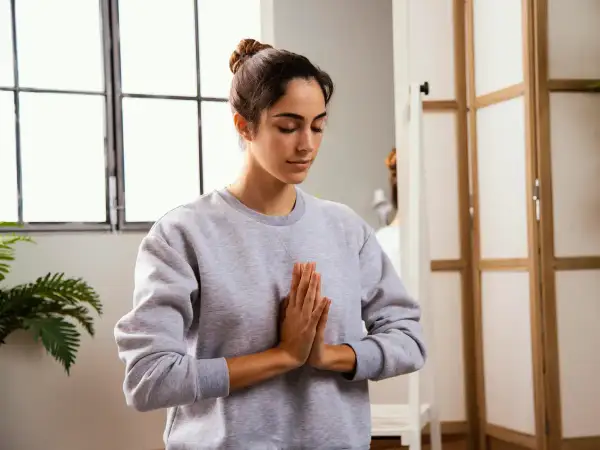 Mujer practicando mindfulness para combatir el insomnio, con las manos juntas en posición de rezo.