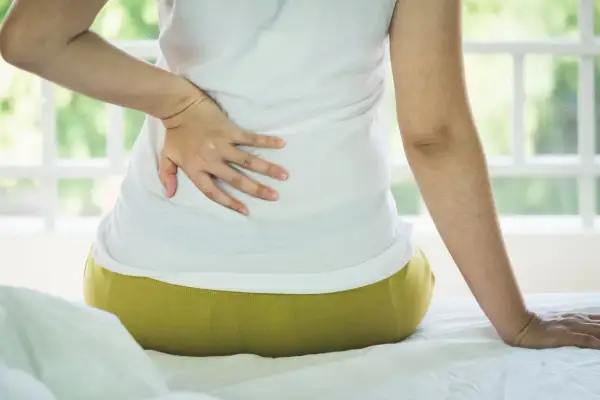 Persona con dolor de espalda, buscando cómo dormir con escoliosis.