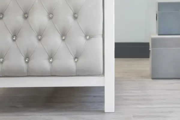 Detalle de un cabecero capitoné gris con botones de cristal. El capitoné es una técnica de tapicería que crea un efecto acolchado y lujoso.