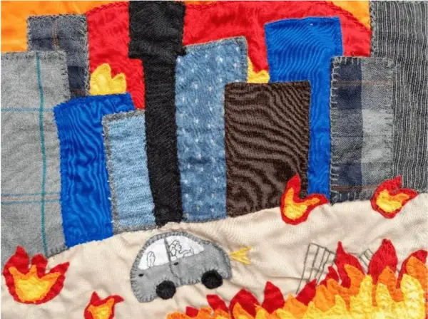 Arpillera que representa una ciudad en llamas. Un coche gris con figuras dentro huye del fuego.