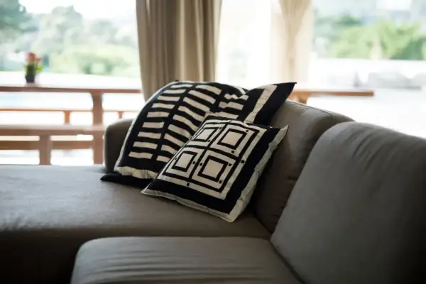 Sofá gris con cojines de diseño geométrico blanco y negro. Un detalle perfecto para combinar sofá negro y crear un ambiente moderno.