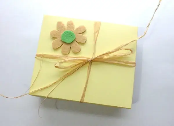 Caja amarilla decorada con flor de fieltro y lazo de rafia. Ideas de manualidades con fieltro para el hogar.