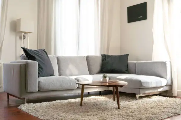 Sofá chaise longue gris con cojines oscuros, ideal para aprender como colocar cojines en chaise longue y crear un rincón acogedor.
