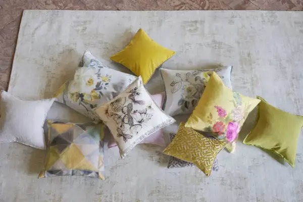 Varios cojines decorativos, algunos con estampados florales y mariposas, otros con diseños geométricos, todos son cuadros hechos con retazos de tela.